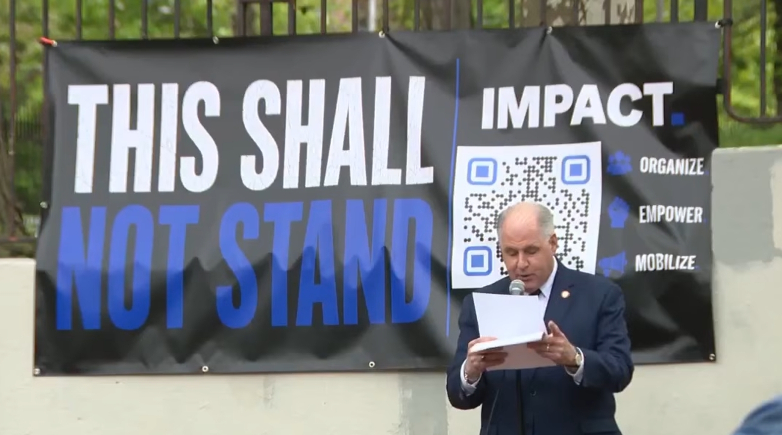 Bruce Blakeman speaks at the Queens rally in front of the IMPACT 'This shall not stand' banner